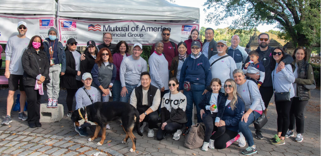 Group of Mutual of America employees posing in front of a tent in a park at the American Cancer Society’s Making Strides Against Breast Cancer Walk