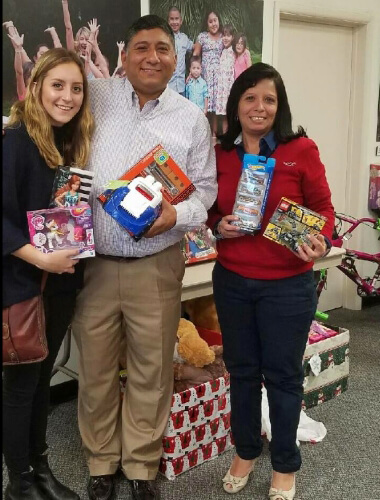 Three Mutual of America employees holding toys at a holiday toy drive